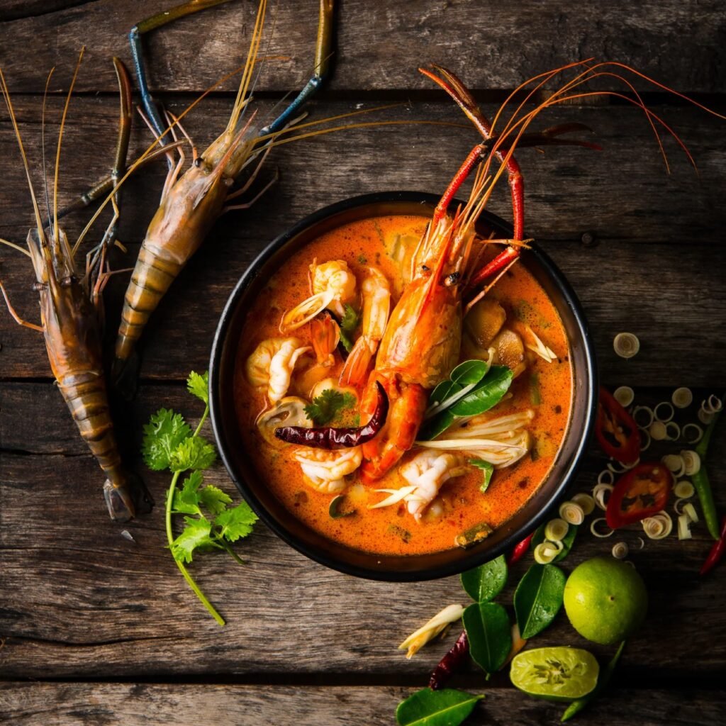Bowl of spicy soup with prawns and fresh herbs